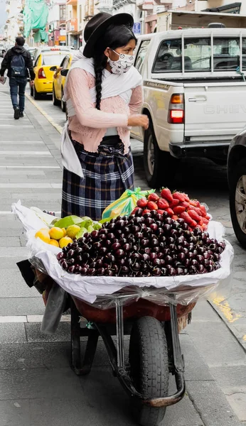 Cuenca, Ecuador, Dec 24, 2021 - Woman sells cherries and fruit from a wheelbarrow — стоковое фото