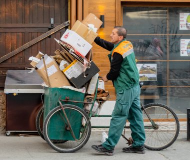 Sarajevo, Bosnia - May 2, 2022 - Man with tricycle loaded with cardboard to recycle.
