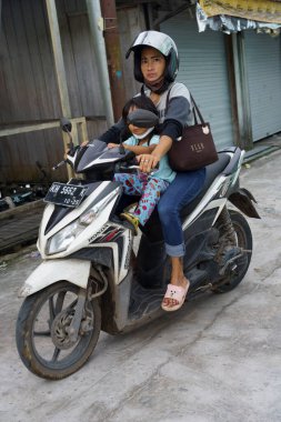Central Kalamantan, Indonesia, May 20, 2022 - woman rides motorcycle with baby.