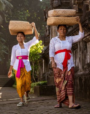 Woman carries basket on her head as she walks.