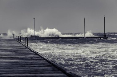 Siyah beyaz fırtınalı bir günde Frankston rıhtımında dalgalar çarpışıyor.