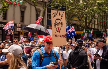 Melbourne, Victoria Avustralya - 20 Kasım 2021: Bourke Caddesi Özgürlük Yürüyüşü 'nde Daniel Andrews tabelasını kaldırıp Bill Peaceful Pro' yu Öldürürken telefondaki mavi gömlekli ve kırmızı şapkalı adam