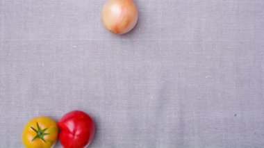 Taze olgun sebzeler çarşaf örtüsünün üzerine düşer. Hareketi durdur