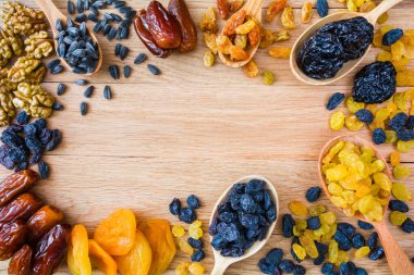 Ahşap bir arka planda farklı kurutulmuş meyve, fındık ve tohumlar çerçevesi