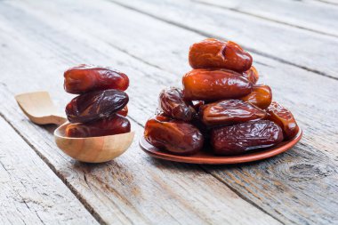 Tahta bir masanın üstünde kurumuş hurmalar.