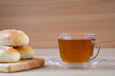 Tahta bir masada susam tohumlu çay ve çörekler.