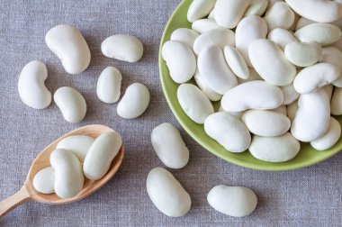 Tabakta büyük beyaz fasulye ve keten bir bezin üzerine serpilmiş.