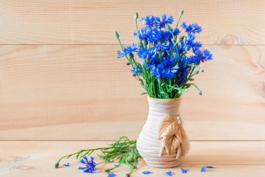 Ahşap bir arka planda vazoda mavi çiçek buketi