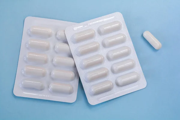 White blisters for 10 pills in capsules on a blue background