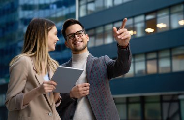 Başarılı iş arkadaşları dijital cihazlar üzerinde birlikte çalışıyorlar. İş adamları şehir konsepti üzerinde çalışıyor