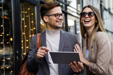 Başarılı iş arkadaşları dijital cihazlar üzerinde birlikte çalışıyorlar. İş adamları şehir konsepti üzerinde çalışıyor
