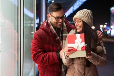 Birbirine aşık güzel genç bir çift dışarıda hediyeyle kutlama yapıyor. Noel doğum günü hediye günü konsepti