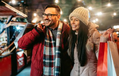 Romantik Noel alışverişi. İndirim ve insan konsepti. Mutlu genç çift aileye hediye alıyor.