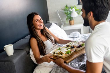 Mutlu adam kahvaltıyı yatağındaki güzel kız arkadaşına getiriyor.