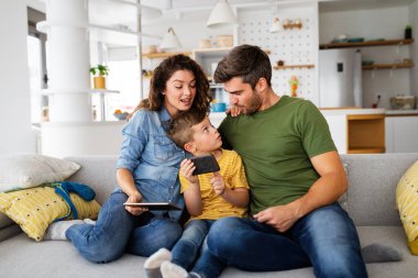 Genç ve mutlu bir aile evde eğleniyor. Teknoloji insanları kavramı.