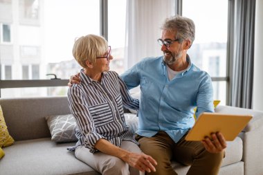 Mutlu, olgun bir çift evde birbirine sarılıyor ve gerçek duygularla kaynaşıyor.