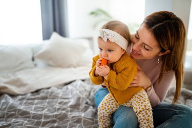 Mutlu bir aile. Anne kız oynuyor, sarılıyor, evde öpüşüyorlar.