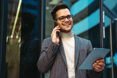 Başarılı genç iş adamı kentsel arka planda dijital tablet üzerinde çalışıyor