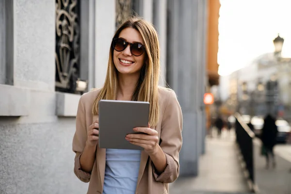 Beautiful young success woman with coffee using digital tablet against urban city background. People business break device concept