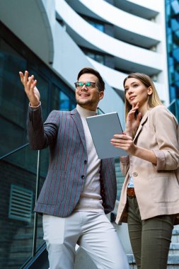Başarılı genç iş adamları, tasarımcılar konuşuyor, modern iş binası önünde birlikte çalışıyorlar.