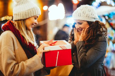 Mutlu genç bayan arkadaşlar Noel hediyelerini değiş tokuş ediyorlar. Mutluluk insanlar arkadaş alışveriş xmas konsepti