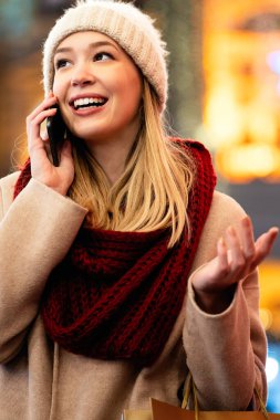 Kışın şehirde cep telefonu kullanan mutlu bir kadının portresi. Halk iletişimi kavramı
