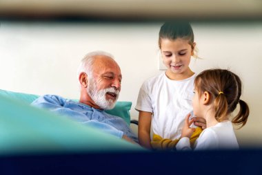 Mutlu kıdemli adam Coronavirus 'tan kurtuluyor. Torunları onu ziyaret ediyor.