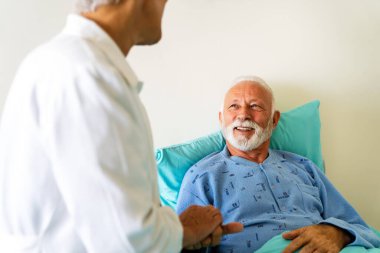 Doktor, hasta yatağında iyileşmekte olan son sınıf erkek hastayla konuşuyor. Sağlık hizmetleri, koronavirüs, insanlar konsepti.