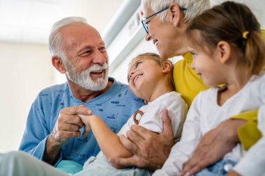 Torunlarını önemsemek, hastane koğuşunda geçirdiği tıbbi ameliyattan sonra dedesine sarılmak. Yaşlı adam klinik terapi sırasında yatakta dinleniyor. Sağlık hizmetleri desteği