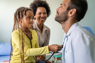 Hastanede bir çocuk hastayı muayene eden bir erkek doktor. Sağlık hizmetleri, insanların korunması kavramı