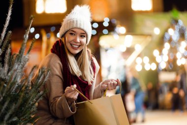 Noel şenliği, kış tatili konsepti. Mutlu gülümseyen kadın Noel pazarında eğleniyor ve alışveriş yapıyor..