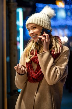 Genç ve güzel bir kadın, bir kış gününde cep telefonunu internette akıllı telefonuyla geziyor. İnsanlar teknoloji mutluluk kavramı