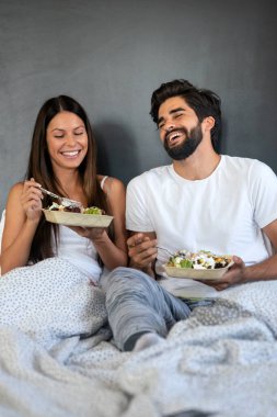 Yatakta sağlıklı bir kahvaltı. Genç ve güzel bir çift yatakta kahvaltı yapıyor..