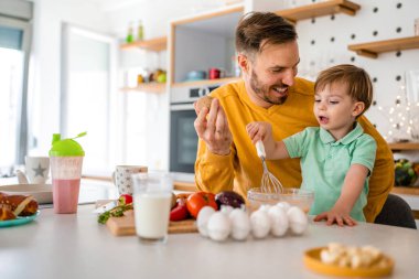 Mutlu aile evi mutfak konsepti. Çocuklarla gülümseyen baba sağlıklı yemekler hazırlıyor ve birlikte vakit geçiriyorlar.