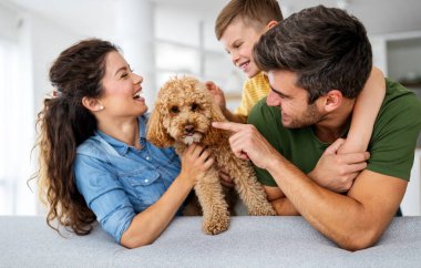 Mutlu genç aile eğleniyor, evde köpeklerle oynuyorlar.