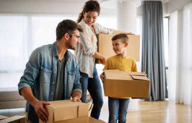 Mutlu aile taşınma gününde yeni evimizde kutuları açıyor. İnsanlar, gayrimenkul, yeni ev kavramı