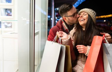 Sokakta alışveriş torbaları taşıyan mutlu bir çiftin portresi. Noel indirimi insanları konsepti