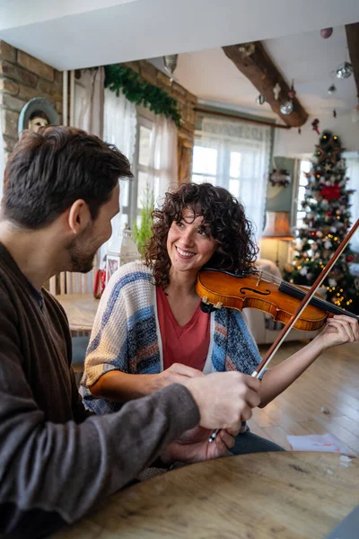Man violin teacher helping a woman student at home