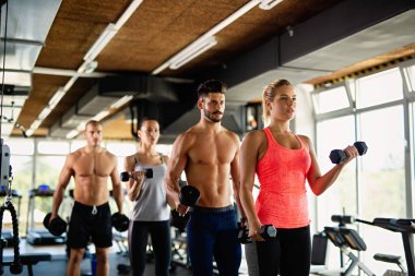 Spor salonunda egzersiz yapan bir grup mutlu zinde genç insan. Spor helatı yaşam tarzı konsepti