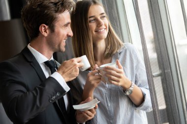 Kahve molası sırasında sohbet eden genç, mutlu profesyoneller.