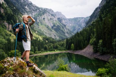 Aktif genç yürüyüşçü, manzaranın tadını çıkarıyor, dağ manzarasına bakıyor.