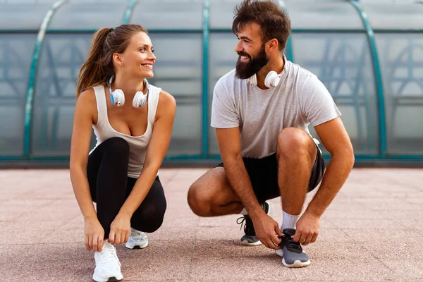 Happy young runner couple exercising outside as part of healthy lifestyle. People sport running concept