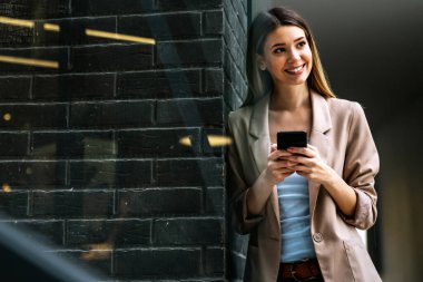 Şehir arka planında cep telefonu olan başarılı bir kadının portresi. İş teknolojisi aygıtı kavramı