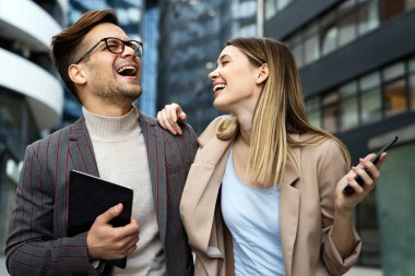 Başarılı genç iş adamları, tasarımcılar konuşuyor, modern iş binası önünde birlikte çalışıyorlar.