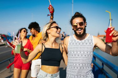 Bir grup mutlu arkadaş yaz festivalinden önce dışarıda içiyorlar.