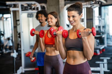 Spor salonunda egzersiz yapan bir grup sağlıklı genç.