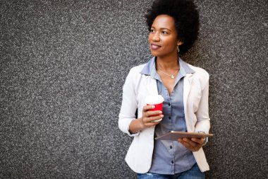 Mutlu iş kadını şehirde kahve molası için tablet kullanıyor.