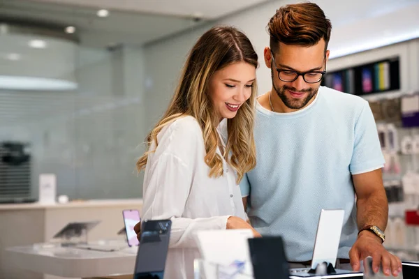 Mobil dükkanından yeni akıllı telefon alan mutlu gençler. Teknoloji Mutluluğu Cihaz Alışverişi