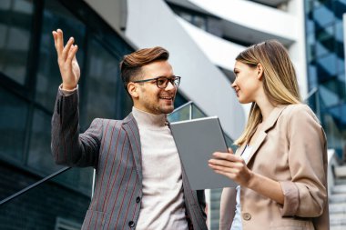 Başarılı iş arkadaşları dijital cihazlar üzerinde birlikte çalışıyorlar. İş adamları şehir konsepti üzerinde çalışıyor