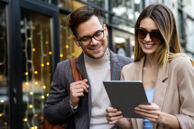 İki başarılı gülümseyen iş adamının portresi. Kentsel arka planda birlikte yürüyüp konuşuyorlar.